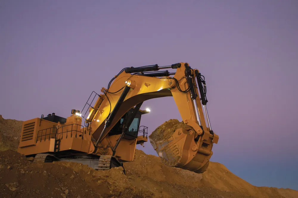 Caterpillar mining excavator loading its bucket at dusk